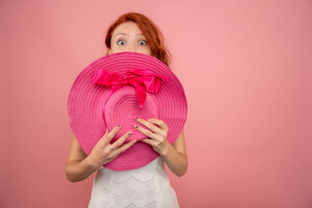 衣服粉红色墙上戴着粉红色帽子的年轻女性的正面图病毒帽子脸
