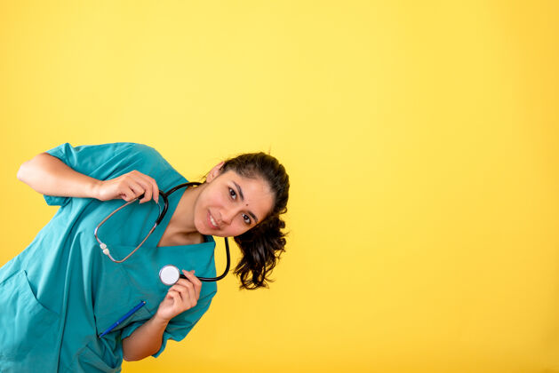 成人黄色墙上带听诊器的年轻女医生的正面图欢乐前面地点