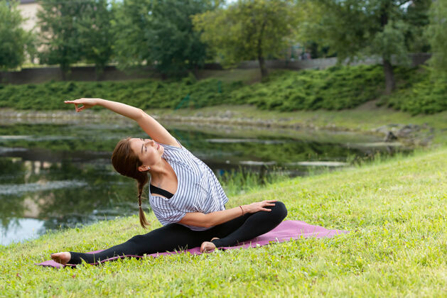 冥想年轻漂亮的女人在绿色公园做瑜伽练习健康的生活方式和健身理念禅宗风景坐着
