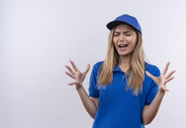 蔓延闭上眼睛 快乐的女孩 穿着蓝色制服 戴着帽子的年轻送货女孩 双手分开放在白色的墙上 留着复印空间穿手帽子