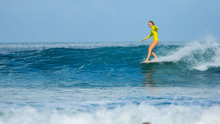 人美丽的冲浪女孩骑长板 做一个鼻子骑把戏阳光放松海滩