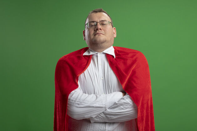 穿着自信的成年斯拉夫超级英雄 身穿红色斗篷 戴着眼镜 以封闭的姿势站在绿色墙壁上 并留有复制空间眼镜信心斗篷