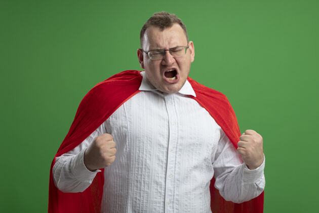 穿着快乐的成年斯拉夫超级英雄穿着红斗篷戴着眼镜在绿墙上做“是”的手势超级英雄成人手势