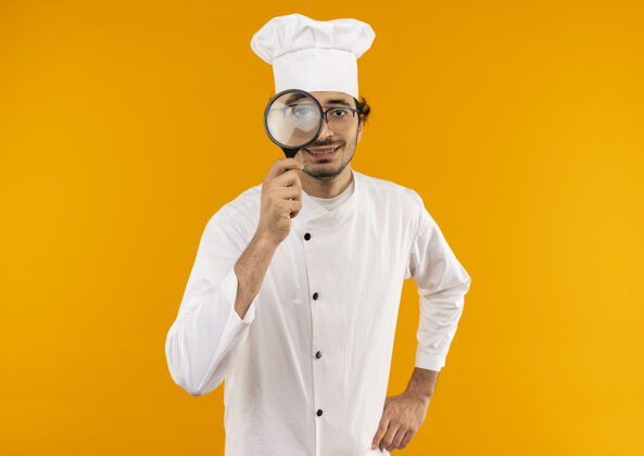 厨师年轻的男厨师穿着厨师制服 戴着放大镜隔离在黄色墙上制服男烹饪