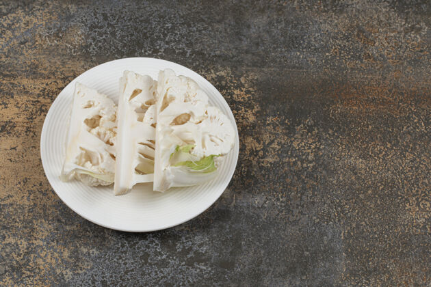 健康把花椰菜片放在盘子里 放在大理石表面有机美味美味
