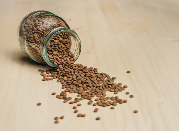 豆类小扁豆的特写镜头散落在玻璃罐的木制表面上种子健康营养