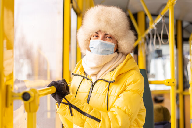 目的地一个穿着暖和衣服的年轻女子在一个冬天的城市公共汽车上的明亮的阳光肖像车站时尚围巾