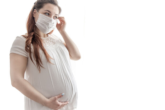 期望穿着白色t恤的准妈妈 脸上戴着防冠状病毒的防护面具怀孕疾病光