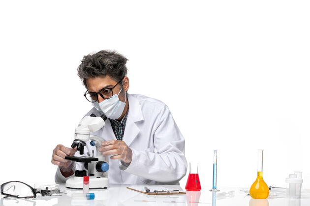 修理前视图穿着白色医疗服的中年科学家正在试图修理显微镜前面专业实验室