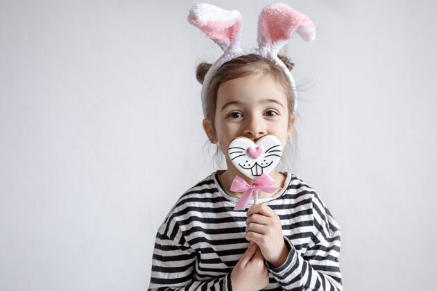 小可爱的小女孩 手里拿着复活节姜饼 头上戴着装饰性的兔子耳朵耳朵美味乐趣