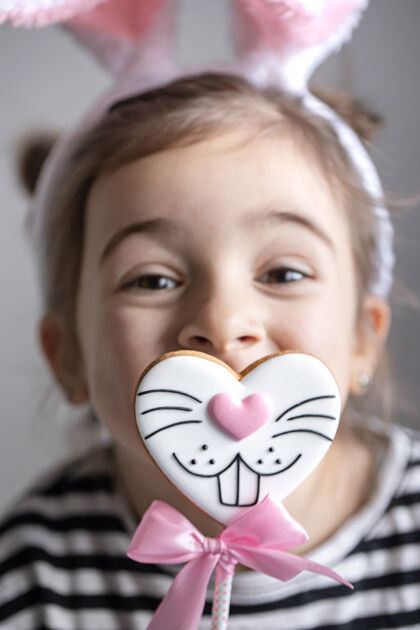 饼干一个小女孩的特写镜头 复活节姜饼放在兔子脸形状的棍子上年轻姜饼人