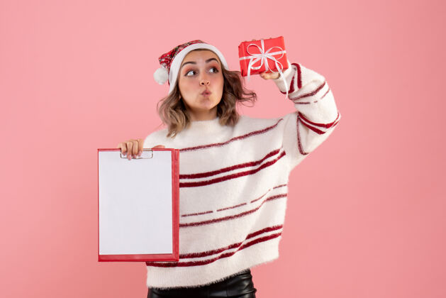 圣诞节年轻的女性拿着小圣诞礼物和粉红色的纸条粉色年轻女性拥抱