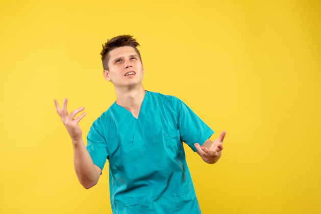 背景正面图黄色背景上穿着医疗服的年轻男医生套装年轻男性医生健康