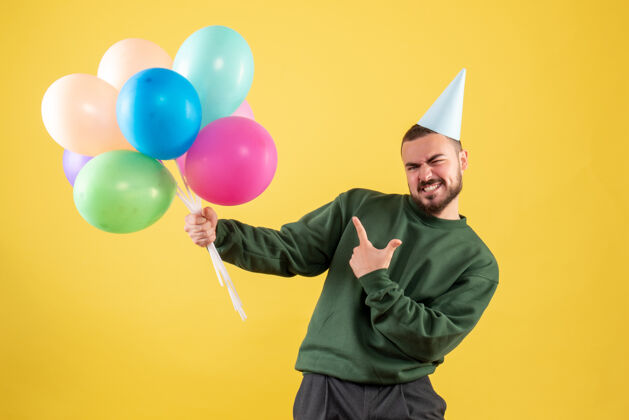 聚会正面图黄色背景上有彩色气球的年轻男性背景气球年