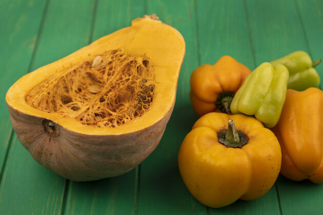 胡椒顶视图美味的橙色南瓜与它的种子和甜椒隔离在一个绿色的木墙上铃铛孩子们种子