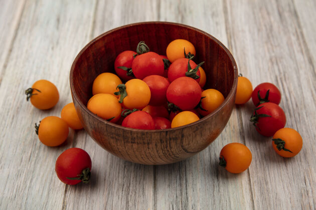 碗新鲜的红色和橙色西红柿的顶视图在一个灰色的木墙上的木碗木材顶部景观