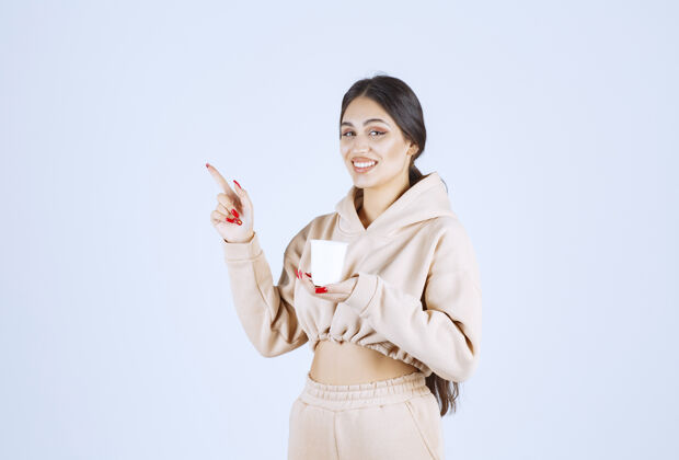 介绍年轻女子拿着一个白色的咖啡杯 给左边的人看姿势人模型