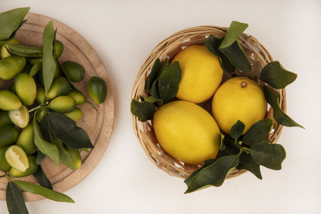 配料水桶上的多汁柠檬俯视图 白色墙壁上的木制厨房板上孤立着金盏花柑橘切片食品