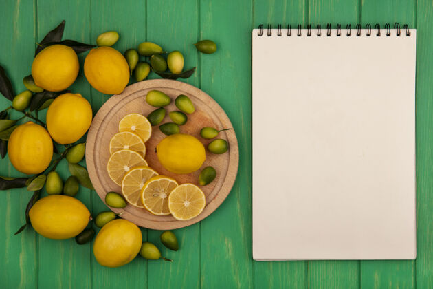 柑橘木制厨房板上有机柠檬的俯视图 绿色木质墙壁上隔离着金盏花和柠檬 还有复制空间食品块板