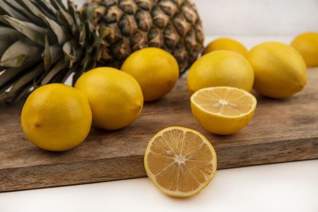 菠萝圆形柠檬和菠萝的俯视图被隔离在白色墙上的木制厨房板上水果顶部厨房