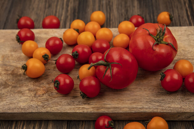 农业有机五颜六色西红柿的俯视图被隔离在木制厨房板上的木制墙壁上番茄板景观