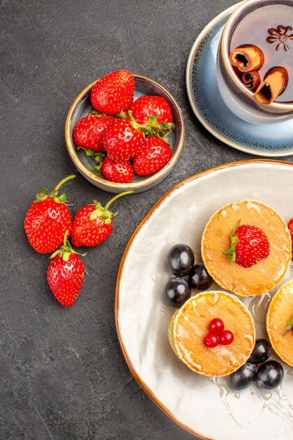 新鲜顶视图小美味的水果煎饼和一杯茶的灰色办公桌馅饼蛋糕水果草莓水果浆果