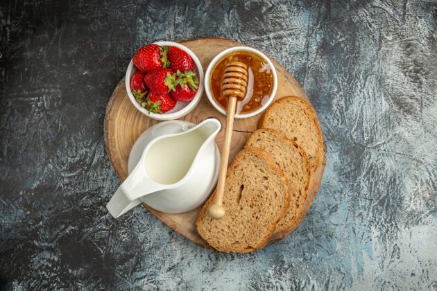 盘子顶视图新鲜草莓与蜂蜜和面包在黑暗的表面水果甜果冻新鲜草莓营养品杯子