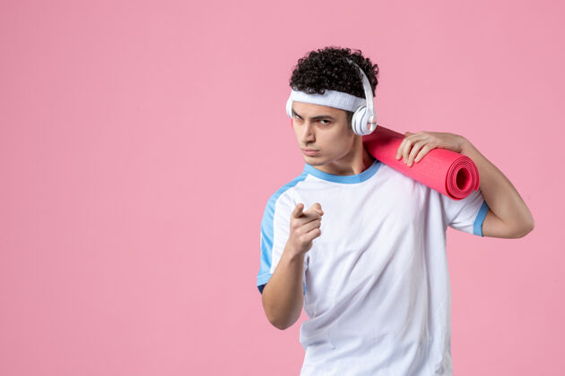 男人正面图穿着运动服的年轻男性运动员 粉色墙上有瑜伽垫成人人锻炼