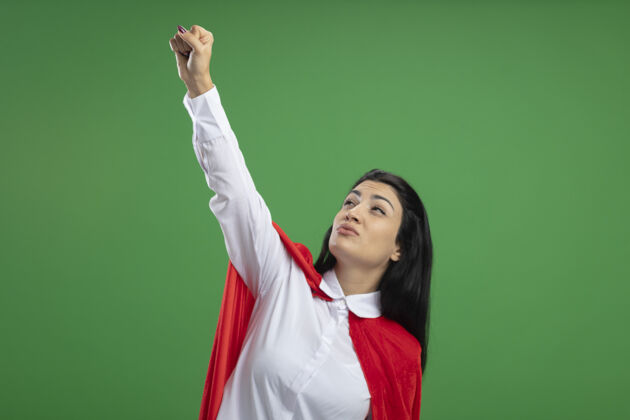 复制自信的年轻白种人超级英雄女孩举起她的拳头 并显示胜利的标志看在绿色背景与复制空间孤立拳头标志女孩
