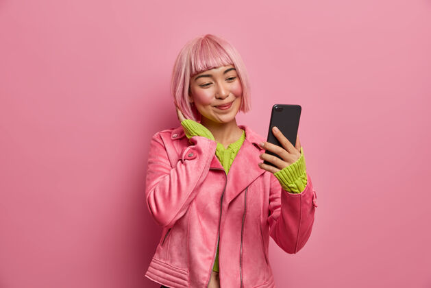 视频迷人的亚洲女孩的肖像在智能手机上自拍 为时尚博客拍摄自己的照片 粉色的发型 积极的微笑漂亮电话自拍