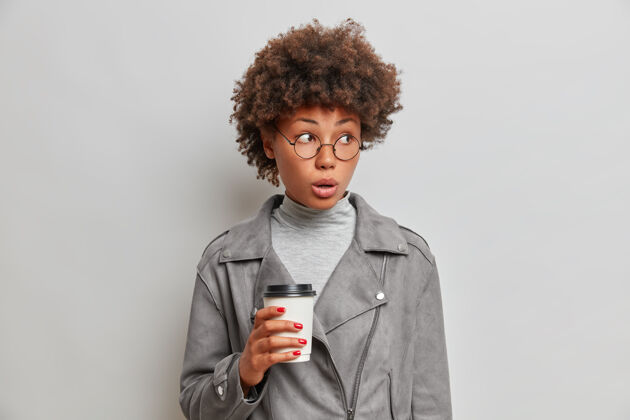 成人穿着灰色夹克的年轻非洲女人喝着外卖咖啡黑发美甲民族