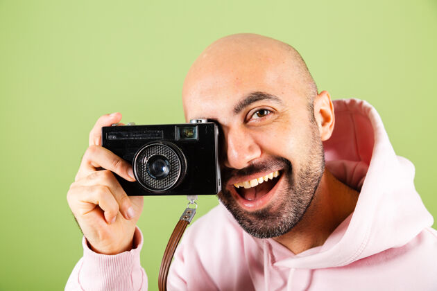 纸杯年轻的秃顶白人男子在粉红色连帽衫孤立 积极的潮人举行相机咖啡拍照数码相机