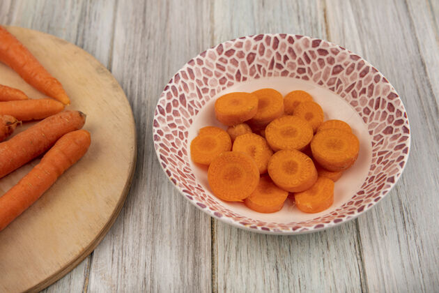 新鲜灰色木墙上碗上的橙色美味切碎胡萝卜俯视图胡萝卜人蔬菜