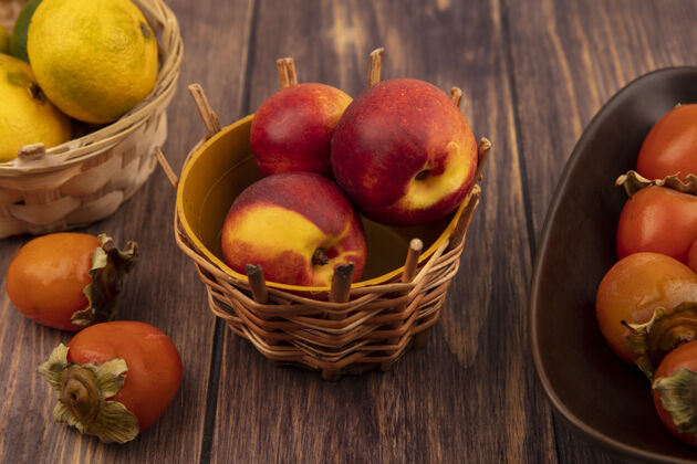 桃木桶上有机桃子的顶视图 木桶上有橘子和柿子顶水果饮食