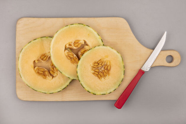 火腿在灰色墙壁上用刀在木制厨房板上的新鲜甜瓜片的俯视图水果夏天刀