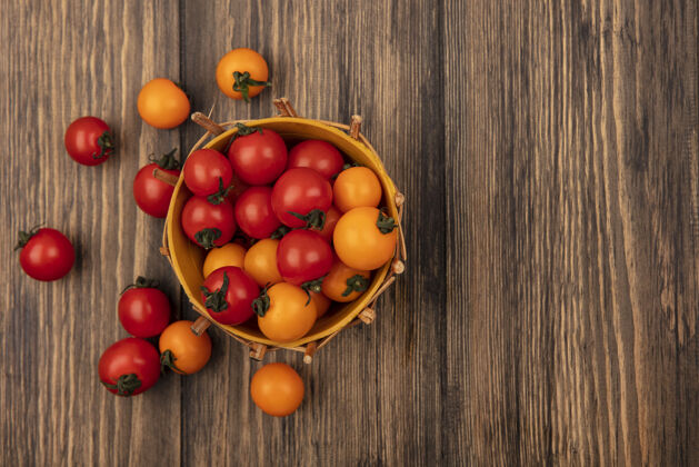 番茄水桶上的多汁的红色和橙色樱桃西红柿的俯视图 西红柿被隔离在有复制空间的木墙上蔬菜农业多汁