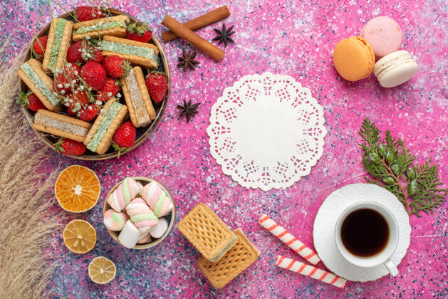 茶俯瞰美味的华夫饼干 新鲜的红色草莓和粉红色表面上的一杯茶华夫饼杯子生的