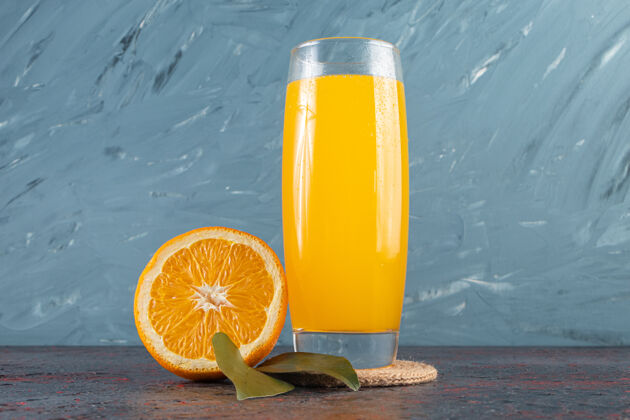 甜点把鲜橙子切成薄片 放在石桌上 放上叶子和一杯果汁橙子自然异国情调