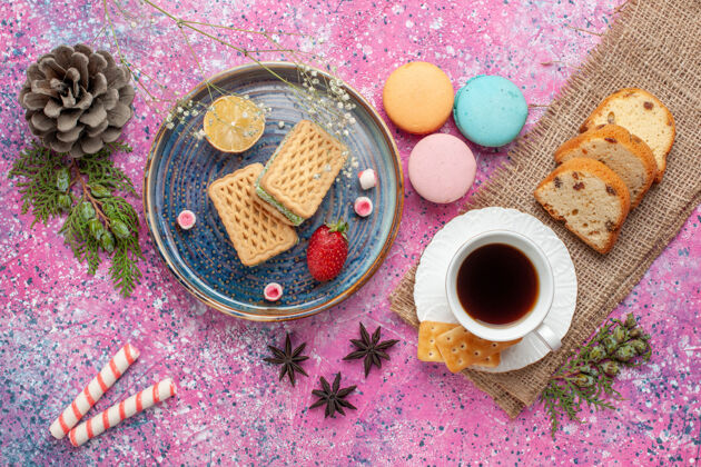 法国俯瞰美味的华夫饼和法国马卡龙 粉色表面上有茶生的治疗粉末
