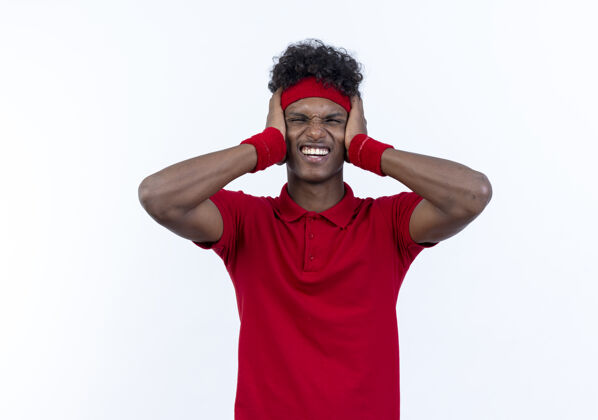 表情紧张的年轻美国黑人运动男子戴头带和腕带封闭的耳朵隔离在白色耳朵紧张男人