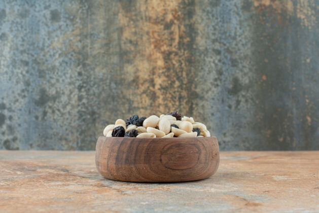 大理石在大理石背景上放满葡萄干和坚果的小木碗木头食物美味