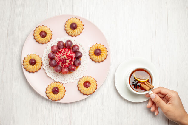 早餐俯瞰美味的葡萄蛋糕和一杯茶放在白色的桌子上甜点饼干派饼干派顶饼干