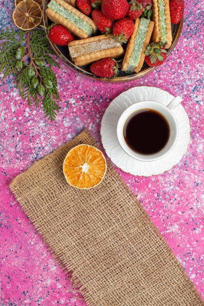 茶俯瞰美味的华夫饼干 新鲜的红色草莓和一杯茶在粉红色的表面美味的杯子华夫饼