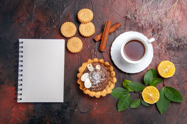 甜点顶视图一杯茶 黑桌子上有小蛋糕和饼干甜点饼干蛋糕记事本咖啡