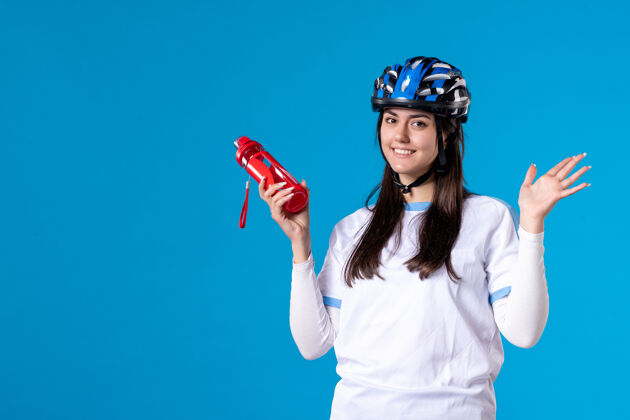 头盔正面图微笑的年轻女子穿着运动服 戴着头盔视图蓝色速度