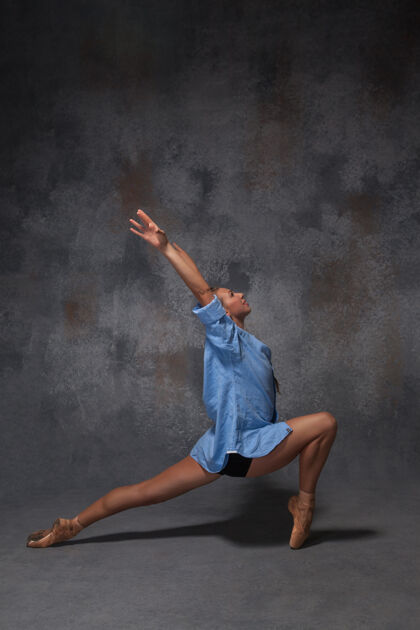 灵活年轻漂亮的现代风格舞者穿着蓝色衬衫在灰色背景上摆姿势动作移动现代
