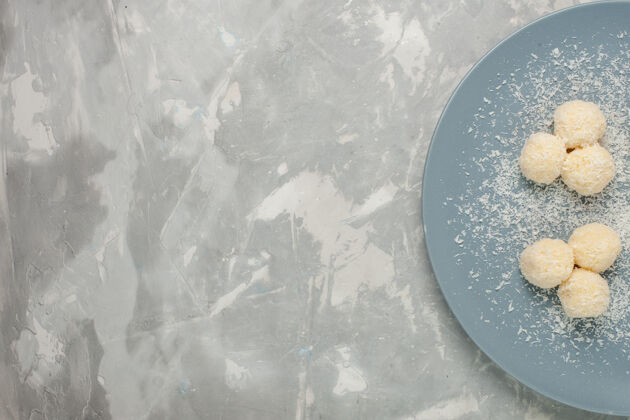 内白色桌子上蓝色盘子里美味椰子糖的俯视图糖椰子顶视图