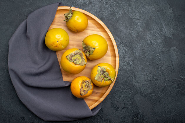 健康顶视图新鲜柿子熟了甜甜的水果放在一张深色的桌子上 水果成熟醇厚食物浆果柿子