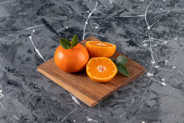 有机大理石桌上放着一盘多汁的橙子和切片的橙子柑橘桔子叶子