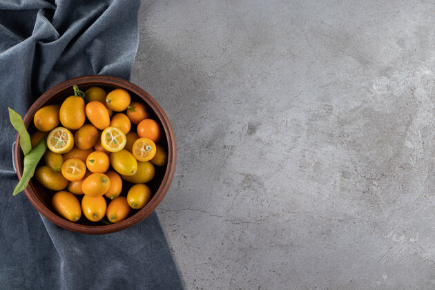 面料金橘果在碗里的一块布上 放在大理石桌上背景可口复制空间